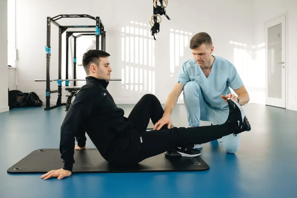 Fisioterapeuta trabajando con un paciente sentado en el suelo de un gimnasio de rehabilitación