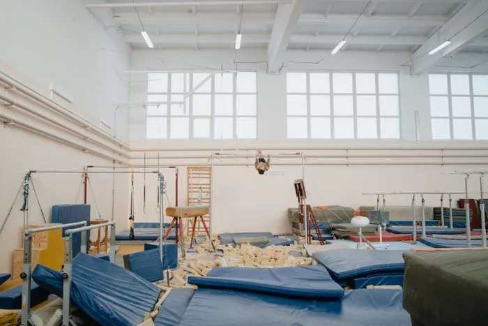 Sala amplia de rehabilitación con barras y colchonetas