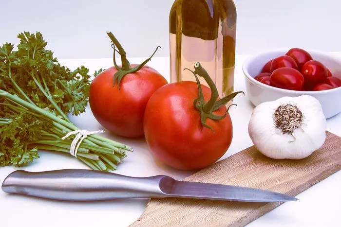 Tomates, ajo y hierbas frescas sobre una tabla de cocina