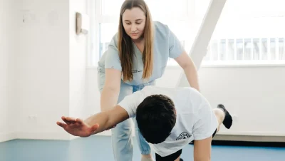 Fisioterapeuta ayudando a un paciente a estirar el tronco y los brazos