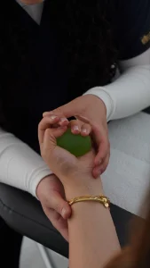 Mano apretando una pelota verde de rehabilitación para ganar fuerza