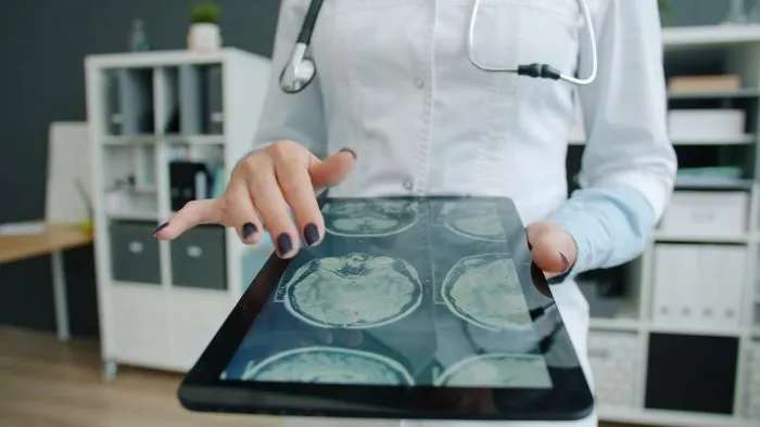 Médico señalando imágenes de escáner cerebral en una tablet