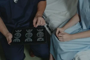 Médico mostrando imágenes de resonancia cerebral en una tablet a un paciente