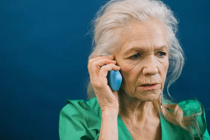 Mujer mayor hablando por teléfono con gesto de preocupación