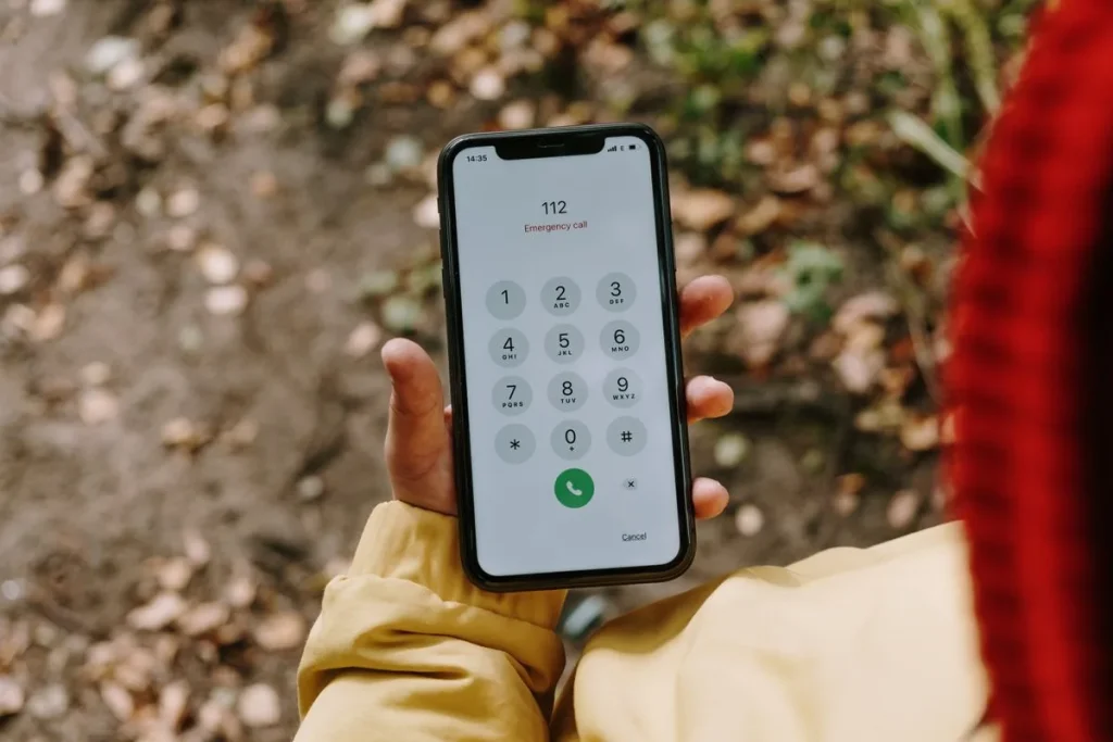 Mano sosteniendo un teléfono móvil con el número de emergencias 112 marcado