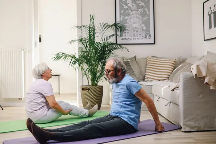 Pareja mayor haciendo ejercicio suave en el salón de casa