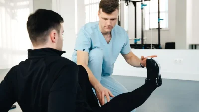 Fisioterapeuta ayudando a un hombre a estirar la pierna en una sala de rehabilitación