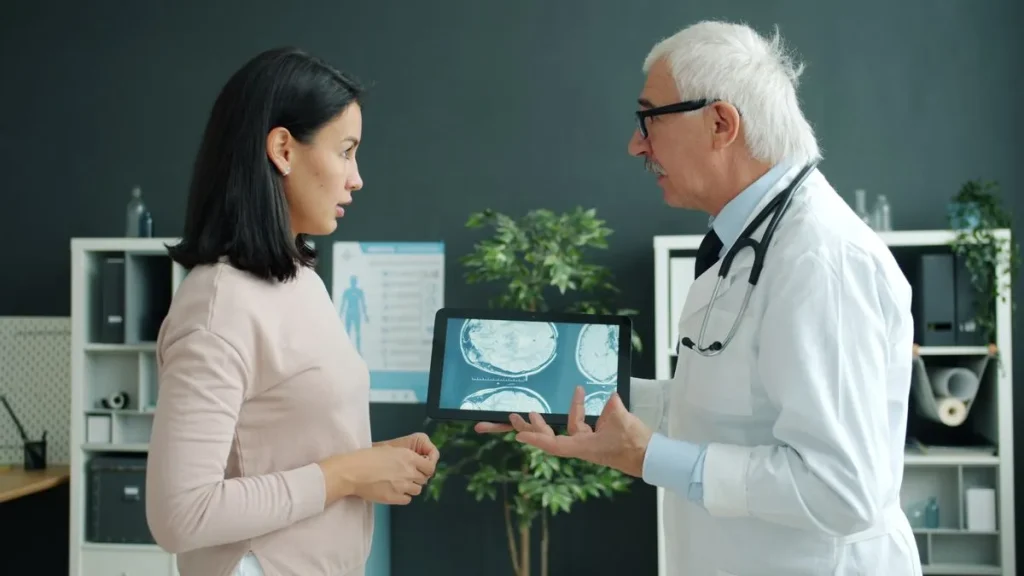 Médico mayor enseñando a una mujer las imágenes de su escáner cerebral en una tablet