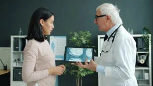 Médico mayor enseñando a una mujer las imágenes de su escáner cerebral en una tablet